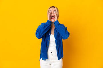 Young Russian woman isolated on yellow background shouting and announcing something