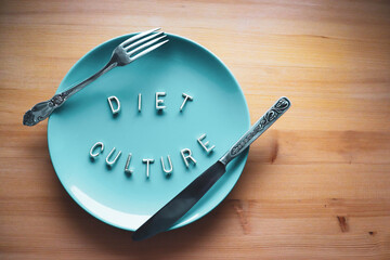 An empty blue plate with a fork and a knife. The letters on the plate say 