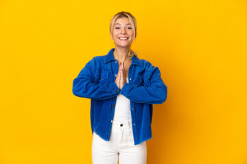 Young Russian woman isolated on yellow background keeps palm together. Person asks for something