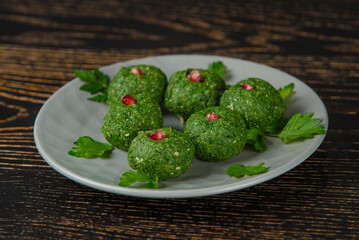 Spinach pkhali decorated with parsley and pomegranate. Georgian appetizer on a gray plate on a dark wooden table.