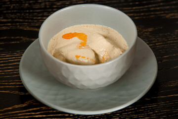 Creamy thick soup with meat in a gray bowl on a dark wooden table.