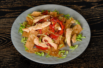 Salad with fried chicken, lavash, pepper, onion and lettuce on a gray plate on a dark wooden table. Georgian cuisine.