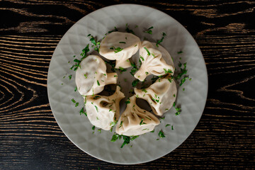 Khinkali traditional Georgian cuisine decorated with cilantro on a gray plate. Top view