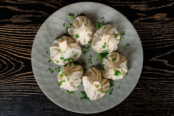 Khinkali traditional Georgian cuisine decorated with cilantro on a gray plate. Top view
