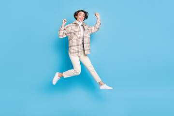 Fototapeta premium Profile full size photo of optimistic funny lady jump wear shirt trousers sneakers isolated on teal color background