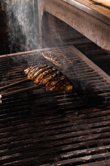 Grilling chicken fillets with metal tongs. The cook prepares a barbecue dish.