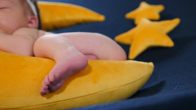 Little infant as model at photo shoot - sleeping and posing on yellow soft toy in Moon shape and stars. Adorable, cute and touching 10-days-old newborn baby sleeping in photo zone, Childhood, infancy