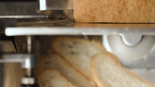 Full aluminium alloy meat slicing machine. Professional electric food slicer. Close-up of stainless steel blade cutting bread.