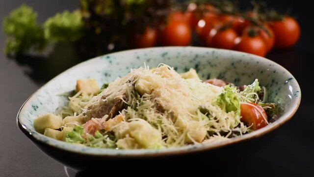Tasty fresh cesar salad rotate on a black table