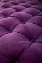 Close up textured purple velvet fabric modern sofa with sunken buttons.