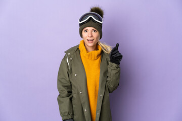 Skier Russian girl with snowboarding glasses isolated on purple background thinking an idea pointing the finger up