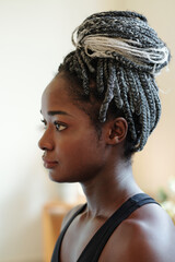 Head of pensive young Black woman with braided hair in bun looking in front of her