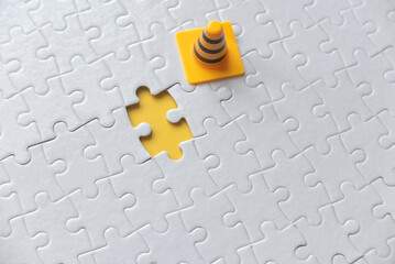 Selective focus of yellow safety cone and an empty space of white jigsaw puzzle with yellow...