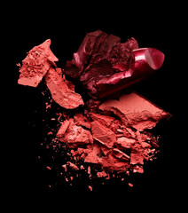 Crushed eye shadow and lipstick isolated on black background