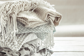 Close up of a stack of cozy Scandinavian style blankets and pillows.