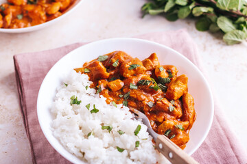 Chicken tikka masala and rice in white bowl on neutral table top
