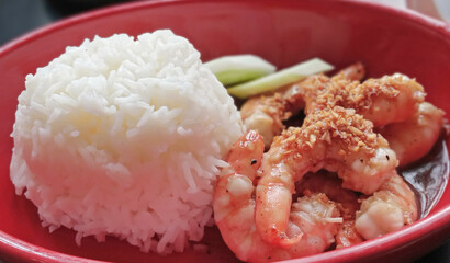White rice with garlic fried shrimp is on a red plate.