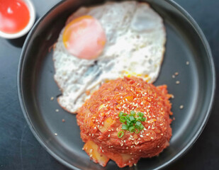 Green vegetables sprinkled on top, kimchi fried rice and fried egg.