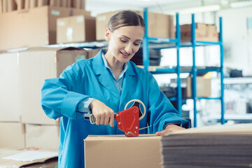 Woman in factory warehouse packaging goods for shipment
