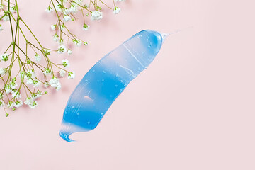 Blue gel smear and white gypsophila flowers on pink background. Natural organic spa cosmetics concept. Top view, lifestyle.