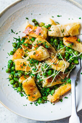 Gnocchi with peas, cheese and herbs, top view. Italian cuisine concept.