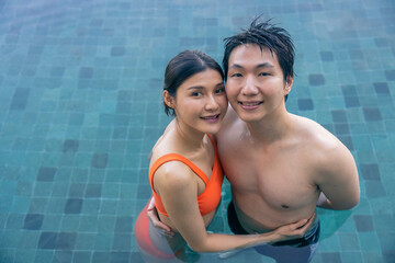 Woman and her boyfriend are happily cuddling in the outdoor swimming pool at the resort, the backdrop of blue sea and sky. Wedding Hannimul trip of a couple. Concept of love, travel, happiness, nature