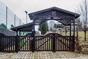 Closed, slatted, black wooden gate of private property. 