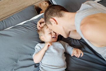 Young father putting child to sleep on his bed, view from above