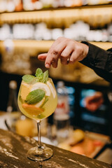 Barman making long drink citrus cocktail at a bar on bar counter.