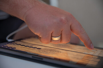 Close up of a mans hand playing backgammon on a tablet.