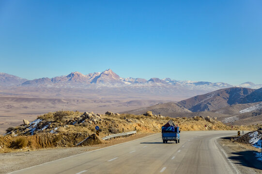 A blue car driving on a scenic road in Iran