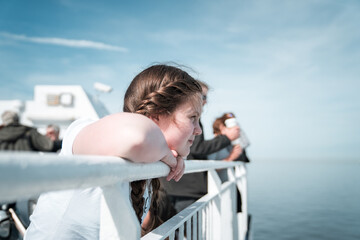 Young pretty girl in sunshine on ferry boat ship deck looking out to sea sailing away from harbour port blue summer skies over English Channel Calais to Dover England
