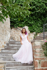 Obraz premium Beautiful woman with purple hair in a white wedding dress walks in the garden. Natural makeup