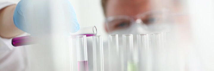 A male chemist holds test tube of glass in his hand overflows