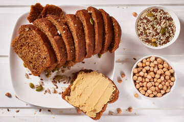 Wholegrain bread with chickpea paste on a white plate and a cup of coffee on the table. Healthy breakfast.