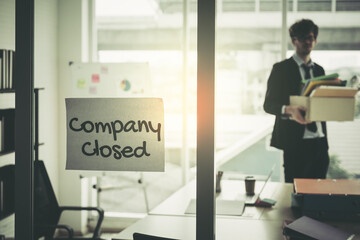 Company closed on windows of an empty office with business man packing beloning walking out of business by economic recession concept. - 420415574
