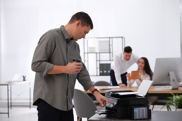 Naklejka na ściany i meble Employee using new modern printer in office