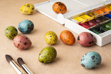 Coloring eggs for Easter. Paints, brushes, quail eggs on a crafting background. Preparation for the celebration of Easter, decorations for the holiday, background. Creative concept