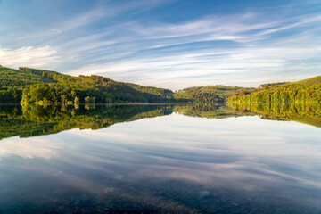 Long exposure at the lake with colorful trees and moving clouds. Soothing landscape photo for backgrounds or quotes.