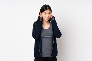 Young sport asian woman isolated on white background listening music