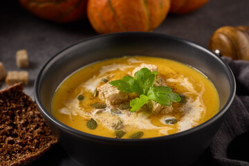 Pumpkin cream soup. Bowl with soup  and orange pumpkins on gray background. Healthy, vegetarian food. Lenten menu