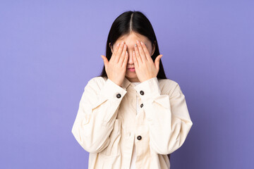 Young asian woman isolated on purple background covering eyes by hands