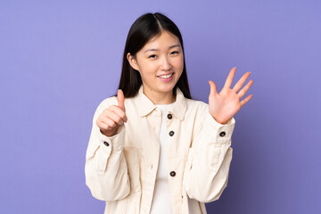 Young asian woman isolated on purple background counting six with fingers