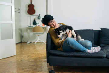 woman embracing with her puppy husky at home