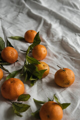 Raw oranges, tangerines on crumpled cloth. Fresh healthy fruits, food background.