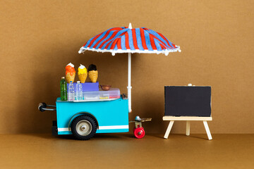 Ice cream toy cart with blue red umbrella. Assortment of ice cream empty menu black chalkboard....