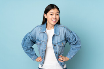 Young asian woman isolated on background posing with arms at hip and smiling