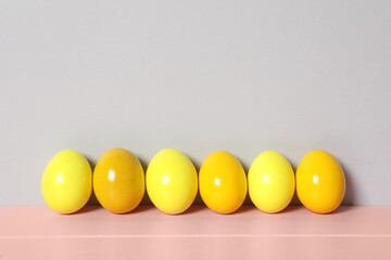 Easter eggs on pink wooden table against light grey background, space for text