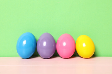 Easter eggs on pink wooden table against green background, space for text