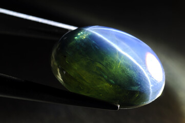 Natural 6 star diffusion treated sapphire cabochon gemstone close up hard spot contrast light. Massive crystal of stone stucture, inpurities, inclusions, crystal grow pattern lines and star lines.